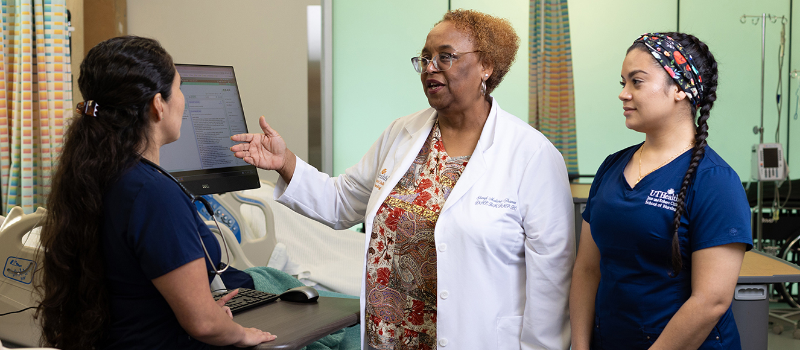 Faculty member demonstrating Epic EHR to two students in the sim lab.