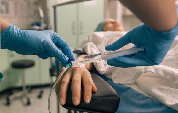 Health care worker injecting medication into an IV. Courtesy Getty Images.