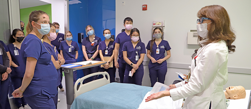 Faculty member speaking to nursing students in the sim lab.