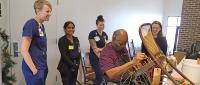 Students participating in the disabilities fellowship at Cizik School of Nursing watch a client repair a chair in the Center for Pursuit’s Cullen Caners workshop.
