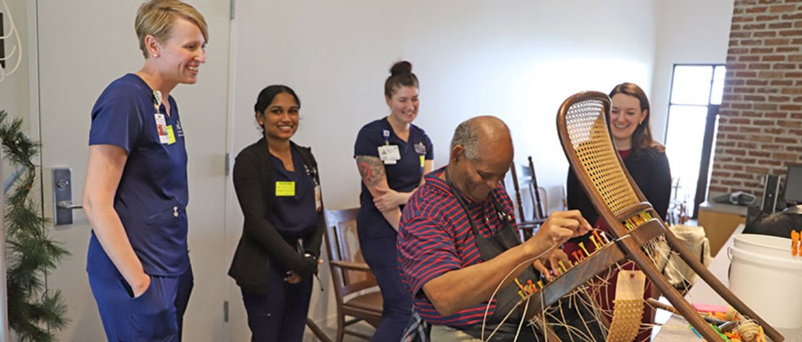 Students participating in the disabilities fellowship at Cizik School of Nursing watch a client repair a chair in the Center for Pursuit’s Cullen Caners workshop.