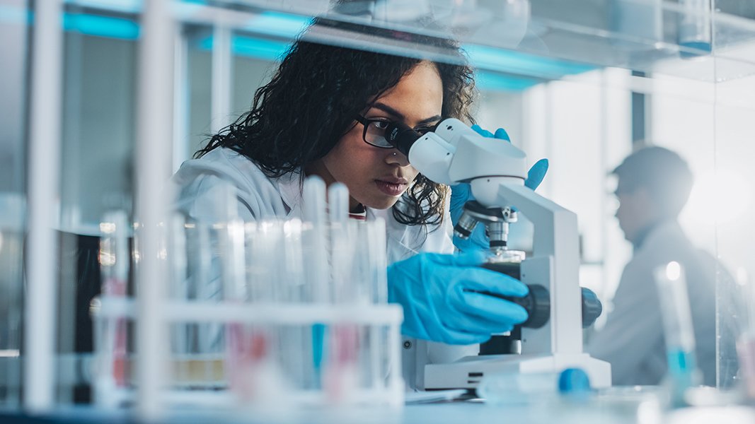 Nurse scientist looking into a microscope