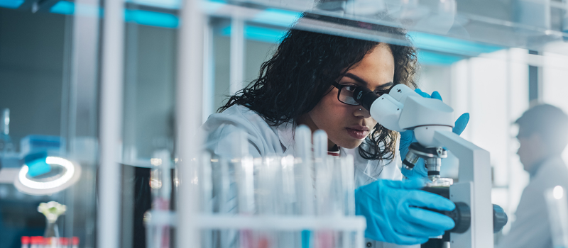 Scientist looking into a microscope. Courtesy Getty Images.