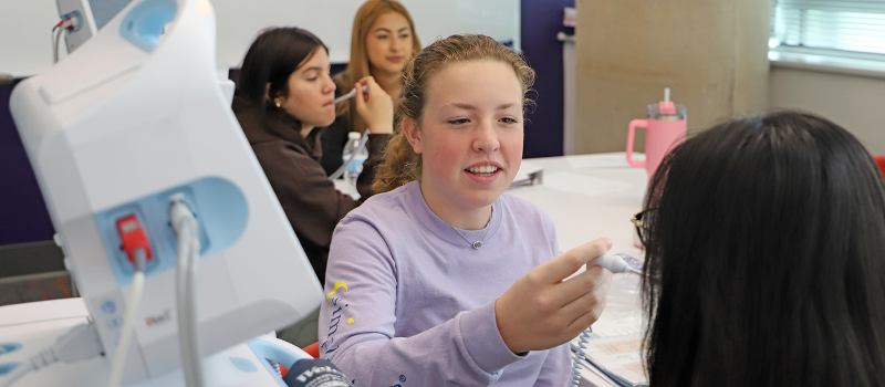 High school students check each others' temperatures in the simulation lab