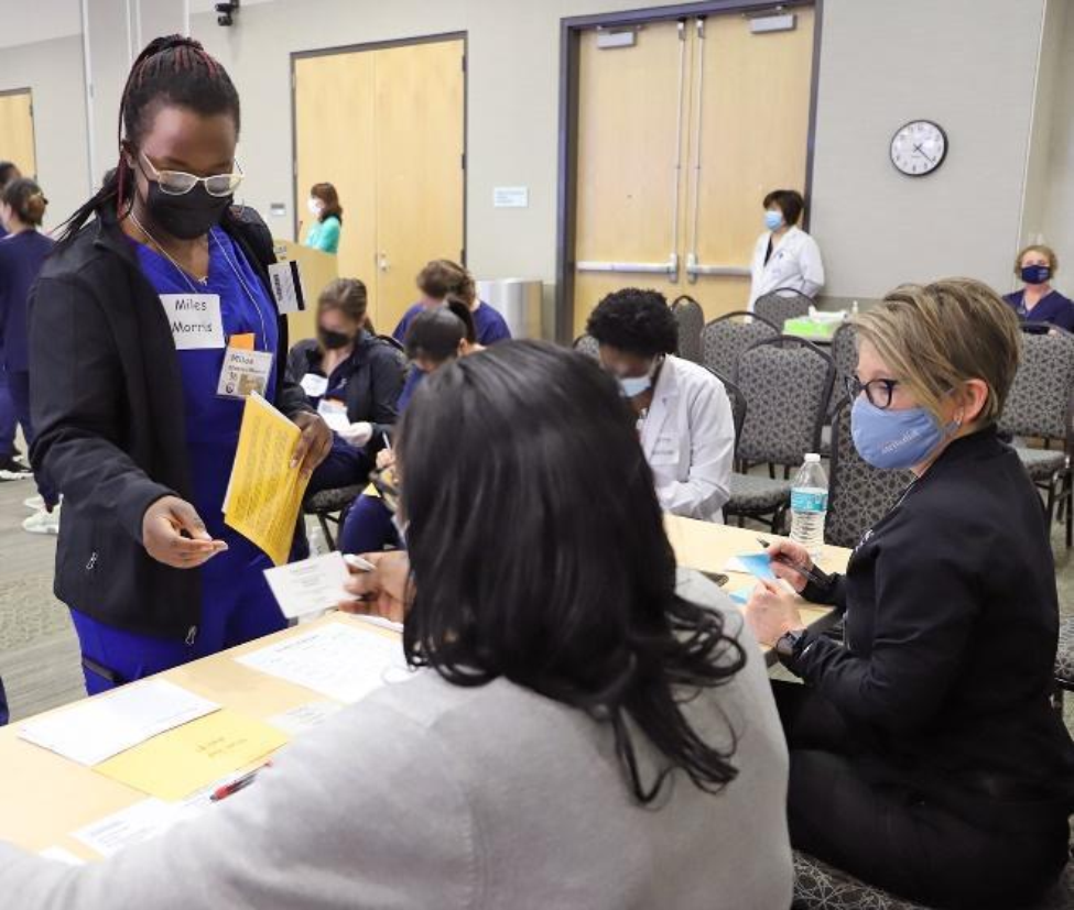 RN-BSN student Goreti Okello pretends to make a mortgage payment during a poverty simulation.