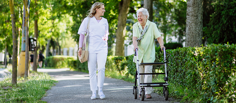 Stock image of nurse walking with older adult woman